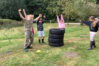 Four pupils standing next to a tower of car tyres