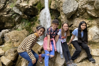 Four children sat by a waterfall