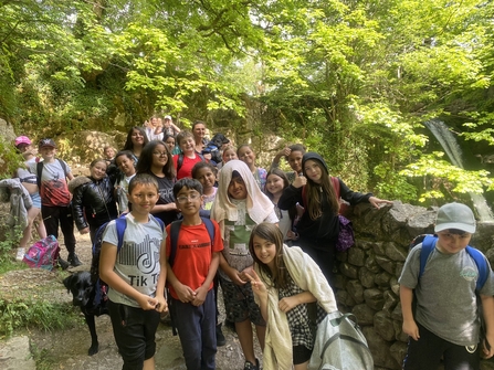 About 20 pupils walking beneath a tree canopy on a school trip