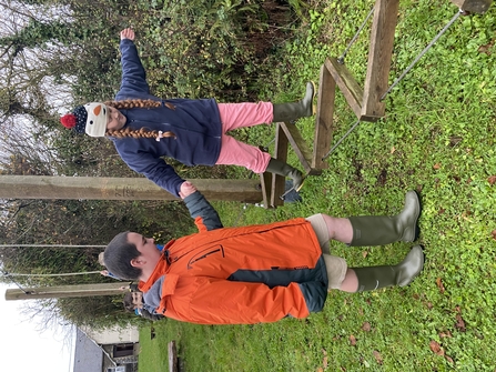 A child taking part in an outdoor obstacle course, helped by an adult